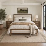 Front room view of a modern upholstered bed with a wood-framed headboard, in a shiplap-walled bedroom with a beamed ceiling.