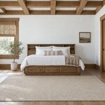 Front room view of a bookcase storage bed with a cubby-lined bookcase back, in a white bedroom with a wood-beamed ceiling.