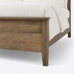 Footboard close-up of a contemporary panel bed, showing the overhanging cap rail, a flat panel and a tapered foot leg.