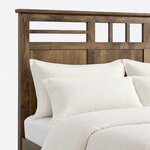 Headboard close-up of a contemporary panel bed, showing the overhanging cap rail, an open lattice and recessed panels.