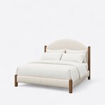 Diagonal angled view showing the left side of a modern upholstered bed, with an arched headboard and square wood posts.