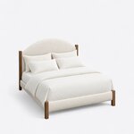 High angled view of a modern upholstered bed, looking down on the arched headboard, upholstered rails and square posts.