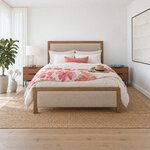 Front room view of a contemporary upholstered bed with a low upholstered footboard, in a white coastal bedroom.