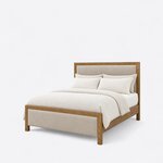 Diagonal angled view showing the left side of a contemporary upholstered bed, with framed upholstered panels at both ends.