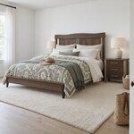 Diagonal angled room view showing the left side of a contemporary panel bed with tapered foot legs, in a white bedroom.