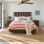 Front room view of a modern slat bed with a metal-barred slat headboard, in a white beach-house bedroom with a surfboard.