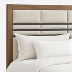 Headboard close-up of a modern upholstered bed, showing padded block panels, horizontal metal bars and a square wood post.