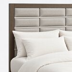 Headboard close-up of a modern upholstered bed, showing padded rectangular panels divided by horizontal metal bars.