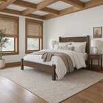 Diagonal angled room view showing the left side of a transitional panel bed with capped posts, in a beamed-ceiling bedroom.