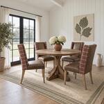 Diagonal angled room view showing the right side of a rustic dining table with a braced pedestal, in a paneled dining room.