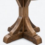 Base close-up of a rustic dining table, showing the curved braces and the rounded foot ends of a cross base.