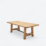 Diagonal angled view showing the left side of a farmhouse trestle table, with a rectangular top and a metal stretcher.