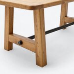 Leg close-up of a farmhouse trestle table, showing a splayed leg and a low cross rail with a round metal fitting.