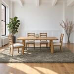 Front room view of a farmhouse trestle table with a round metal stretcher, in a dining room with wainscoting.