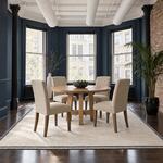 Front room view of a modern pedestal dining table with a splayed open base, in a loft dining room with exposed brick.