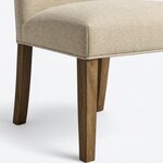 Leg close-up of a Parsons side chair, showing a tapered front leg beneath a rounded seat corner with a welted edge.