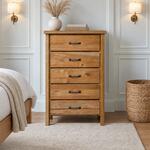 Front room view of a farmhouse chest of drawers with five drawers on square legs, in a white-paneled bedroom.