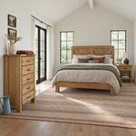 Diagonal angled room view showing the right side of a farmhouse chest of drawers with five drawers, in a vaulted bedroom.
