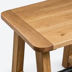 Top corner close-up of a rustic coffee table, showing a rounded corner, an eased edge and a broad end piece.