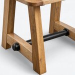 Leg close-up of a rustic coffee table, showing a splayed leg and a metal stretcher with a round collar and a capped end.