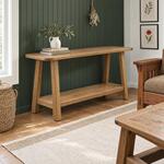 Diagonal angled room view showing the right side of a farmhouse console table with a lower shelf, in a green-paneled room.