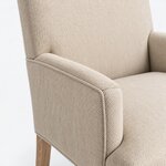 Top corner close-up of an upholstered armchair, showing a rounded arm corner and a welt-trimmed outer panel.