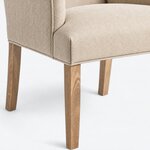 Leg close-up of an upholstered armchair, showing a square tapered leg below a rounded seat corner with welt trim.