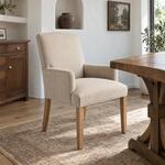 Diagonal angled room view showing the right side of an upholstered armchair with a tall back, in a room with an arched niche.