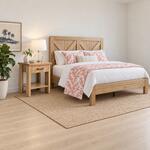 Diagonal angled room view showing the right side of a rustic nightstand with an open shelf, in a coastal bedroom.