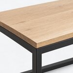 Top corner close-up of an industrial coffee table, with a square corner and an eased top edge above a metal rail.