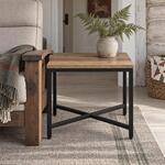 Front room view of an industrial end table with a low metal X-stretcher, in a whitewashed log cabin sitting room.