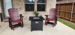 Two burgundy outdoor glider chairs on a patio.