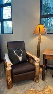 rustic log floor lamp shines light on end table and log recliner